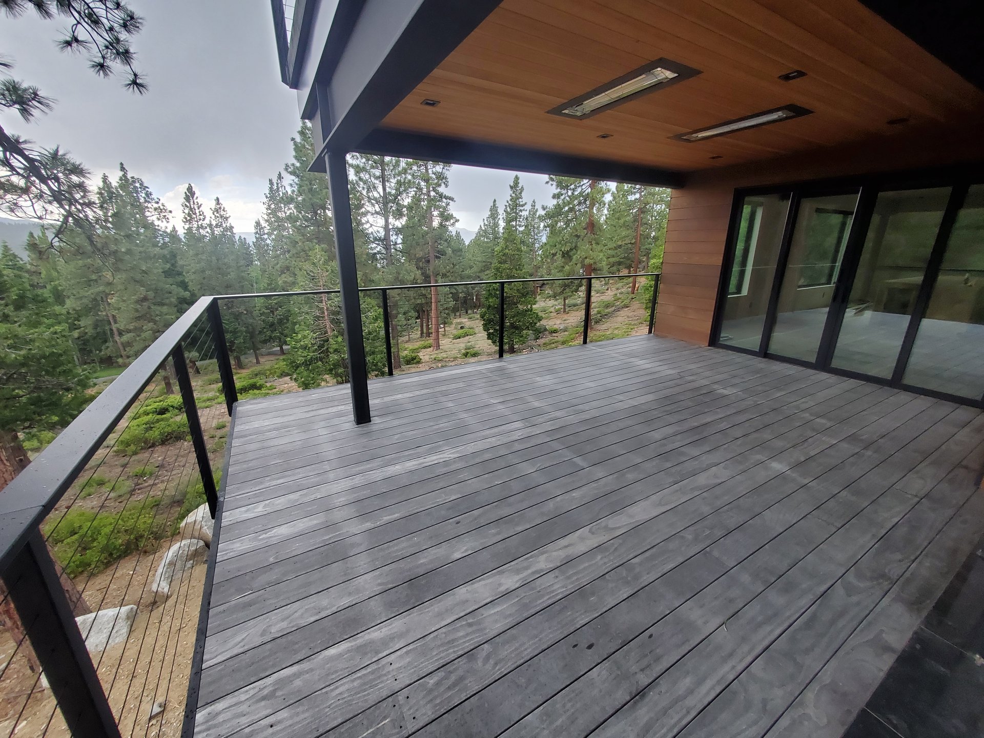 Covered deck with steel framing and cable railing on a finished custom home