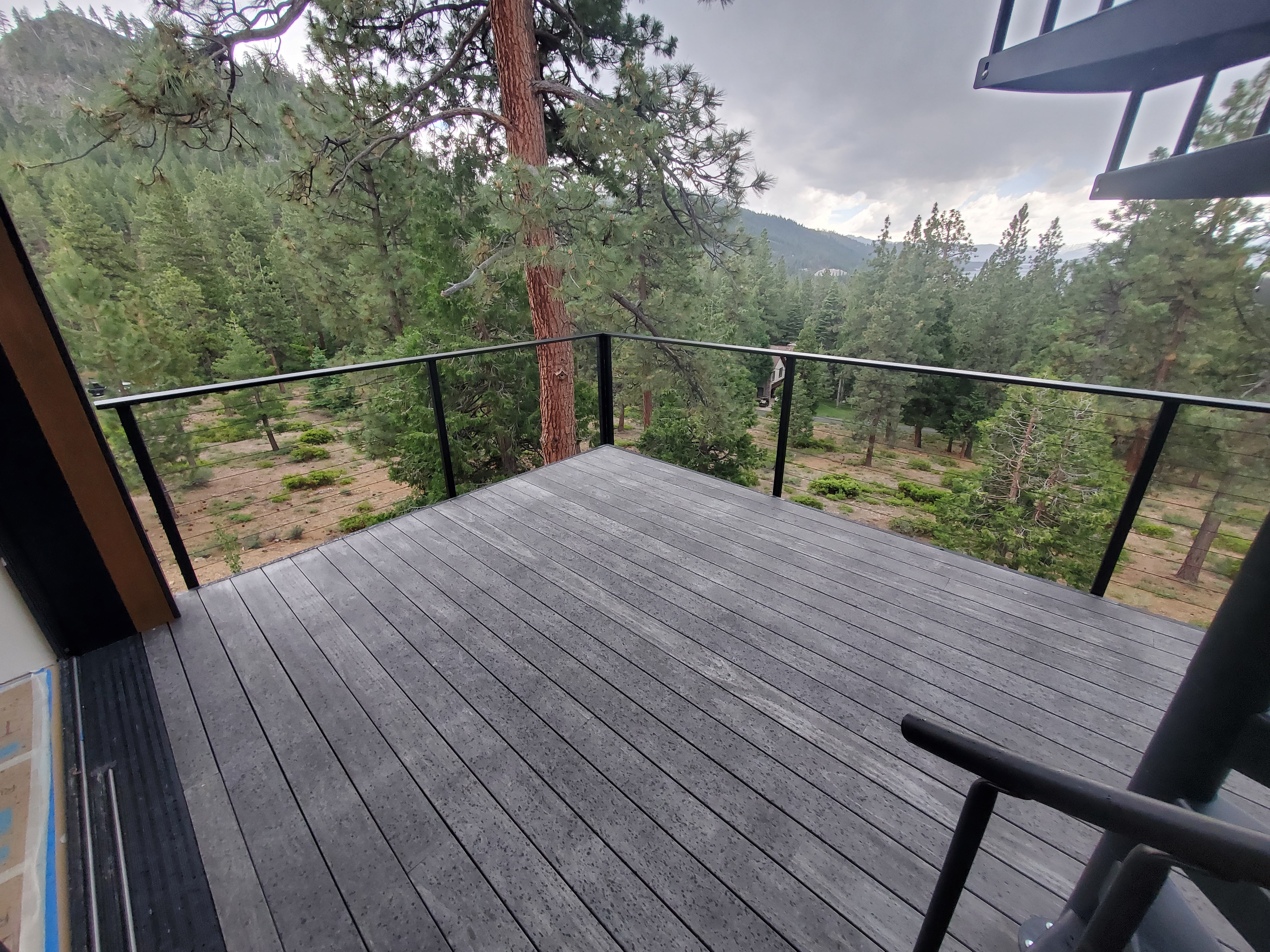 Glass railing on an elevated deck with cable-style infill at Bogowolski Residence